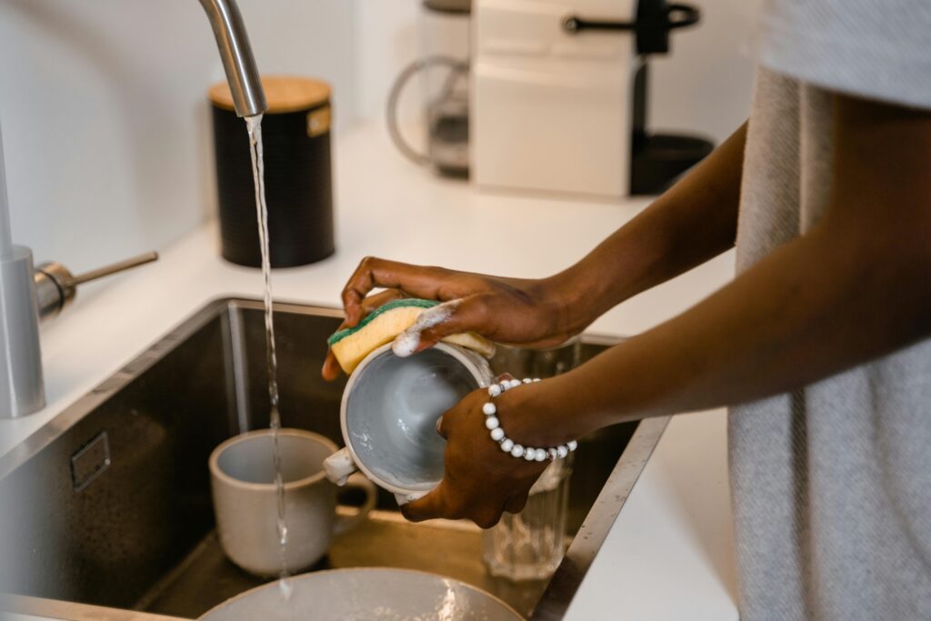 pexels photo 7641411 7641411 Close-up of woman washing dishes at kitchen sink, highlighting hands with bracelet.